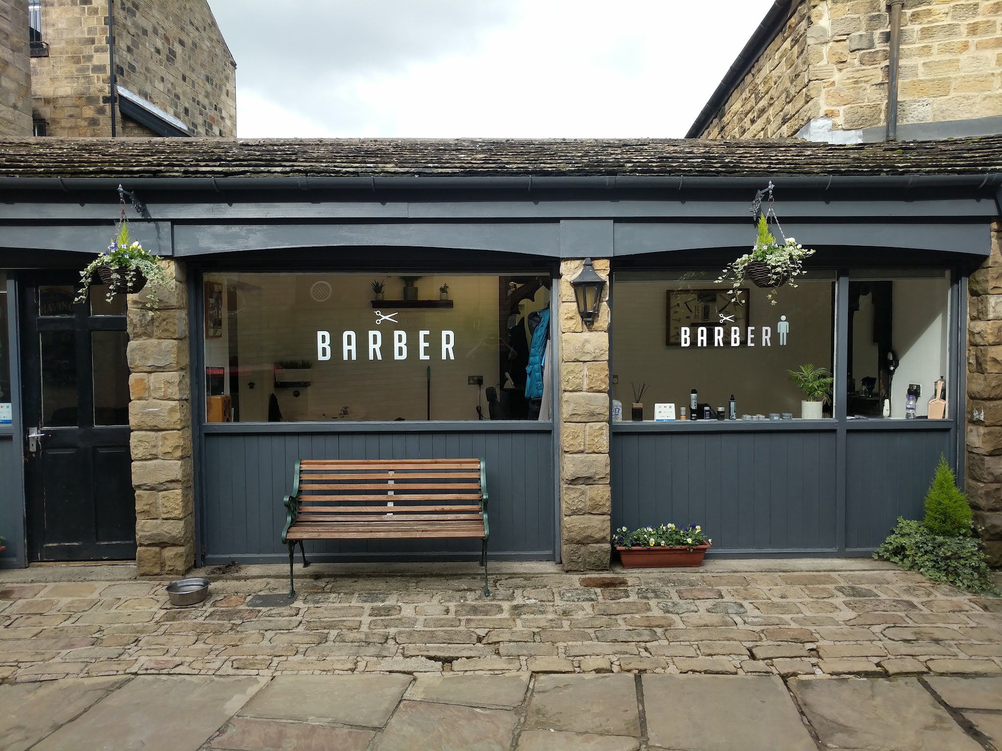The BARBER windows and wooden bench outside the shop in the stone courtyard